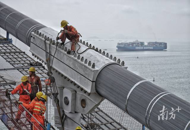 正在施工中的建設(shè)者身后，海上船舶往來(lái)不斷。  